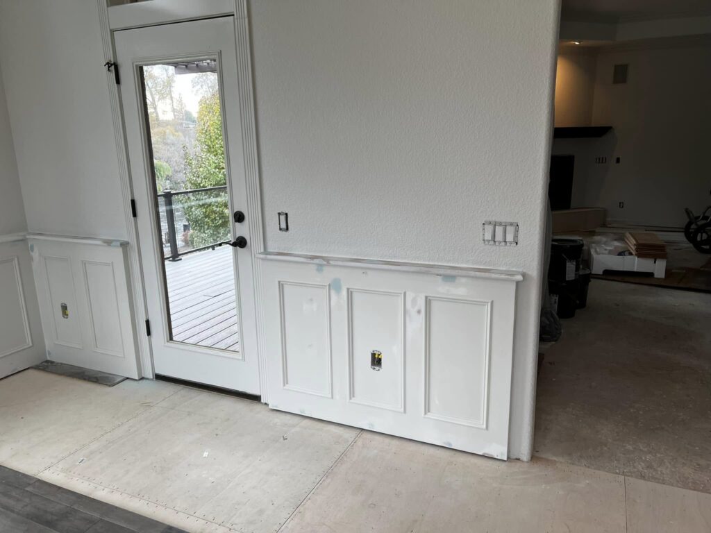 White built-in cabinetry and wall paneling beside an exterior door