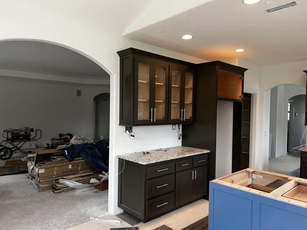 Dark cabinetry and glass-front uppers during installation