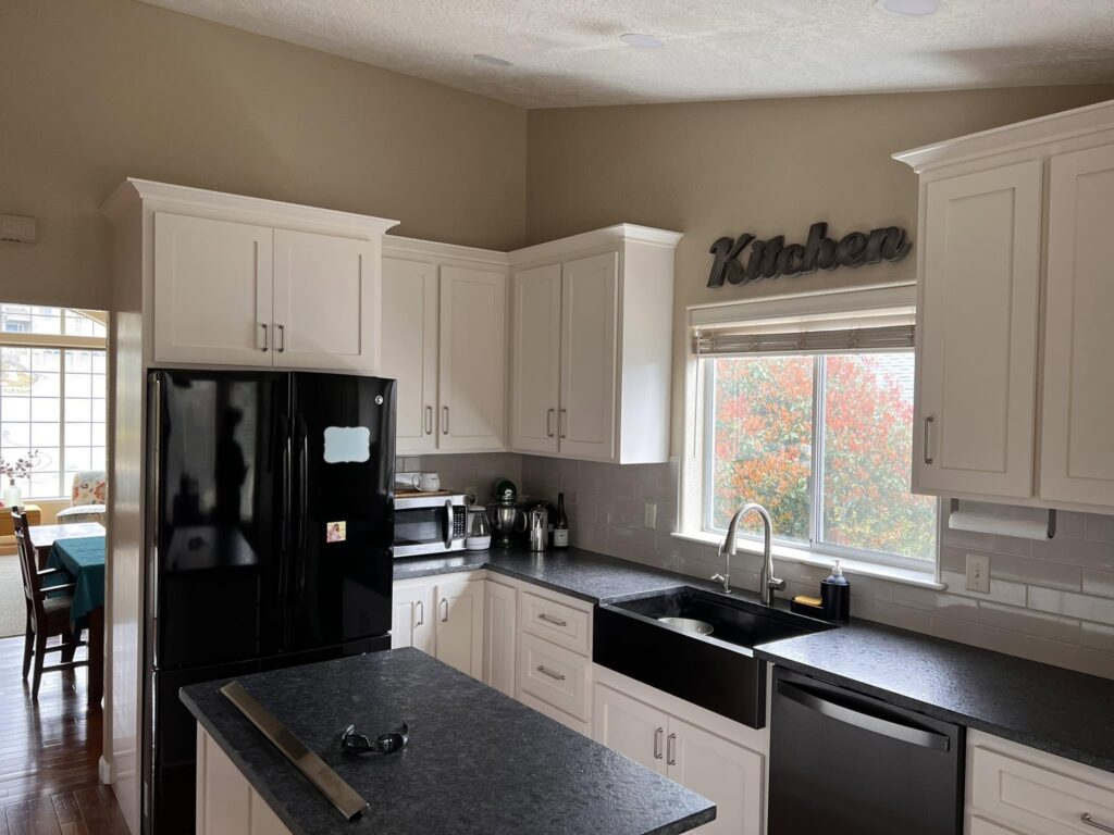 White kitchen cabinets with dark counters and black appliances