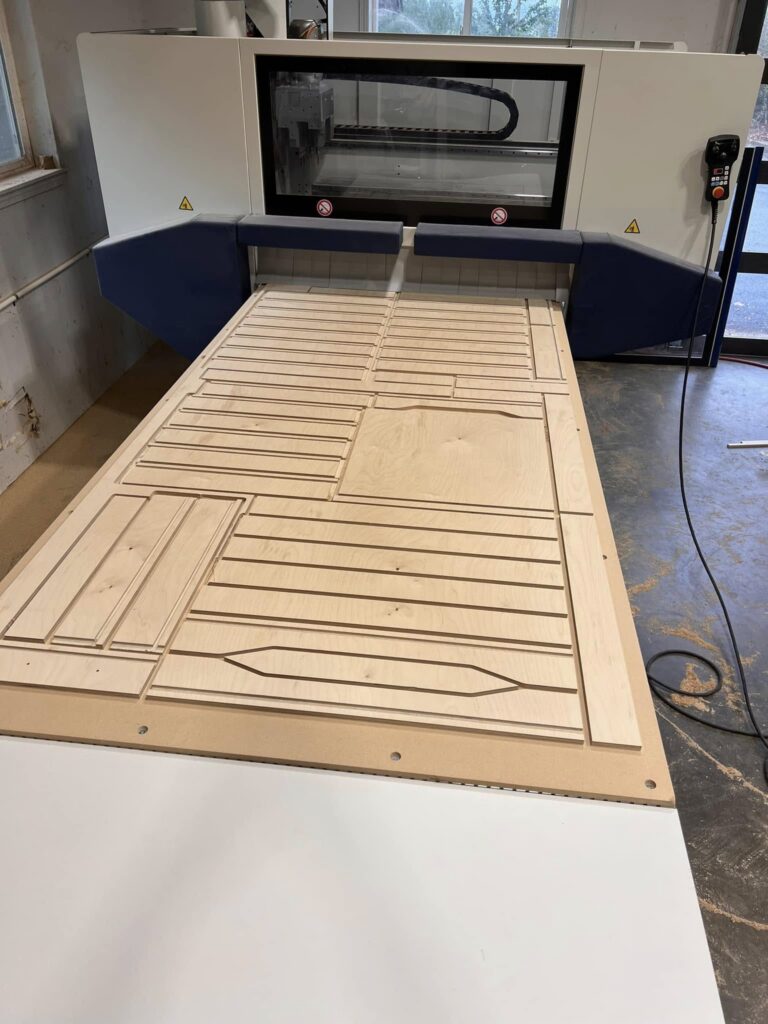 Close view of routed cabinet panel details on a CNC bed