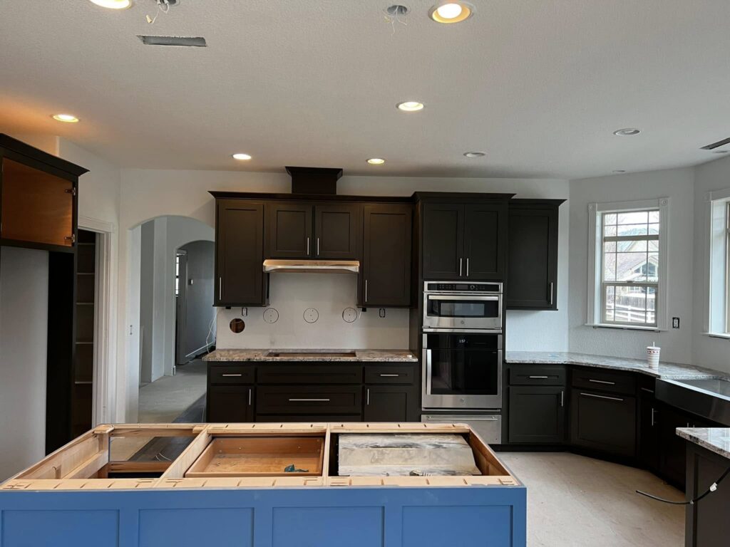 Dark kitchen cabinets and blue island before counters are installed
