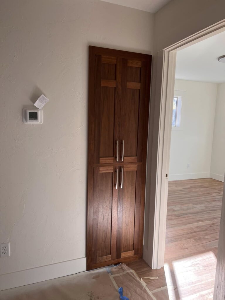 Tall walnut pantry cabinet viewed from an adjacent hallway