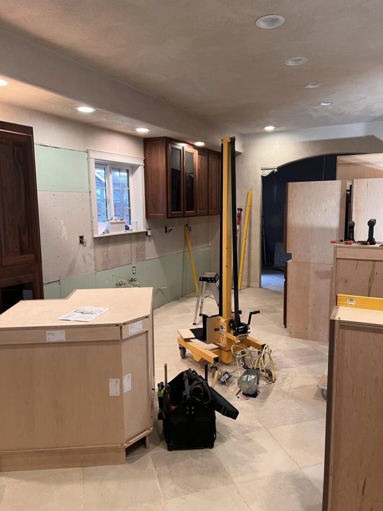 Active walnut kitchen installation with tools and cabinet boxes