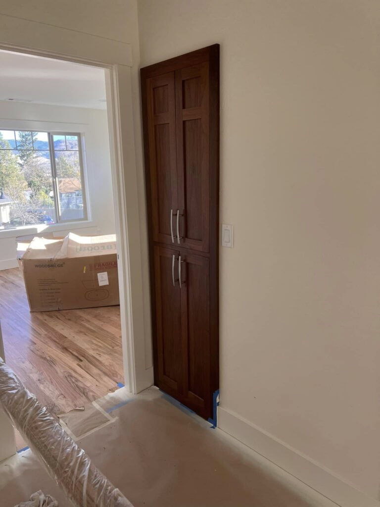 Tall walnut pantry cabinet viewed from inside the adjoining room