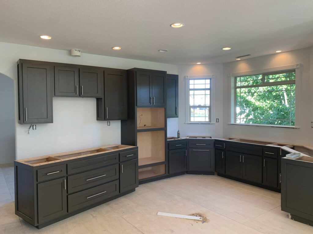 Gray kitchen cabinetry installed around a large window