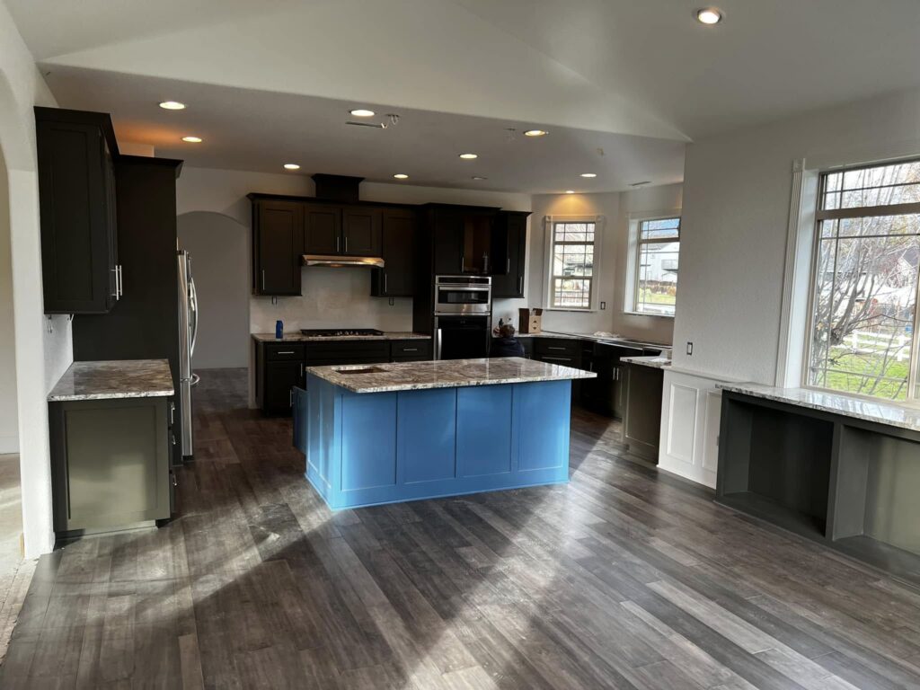 Wide finished view of the blue island and dark perimeter cabinetry