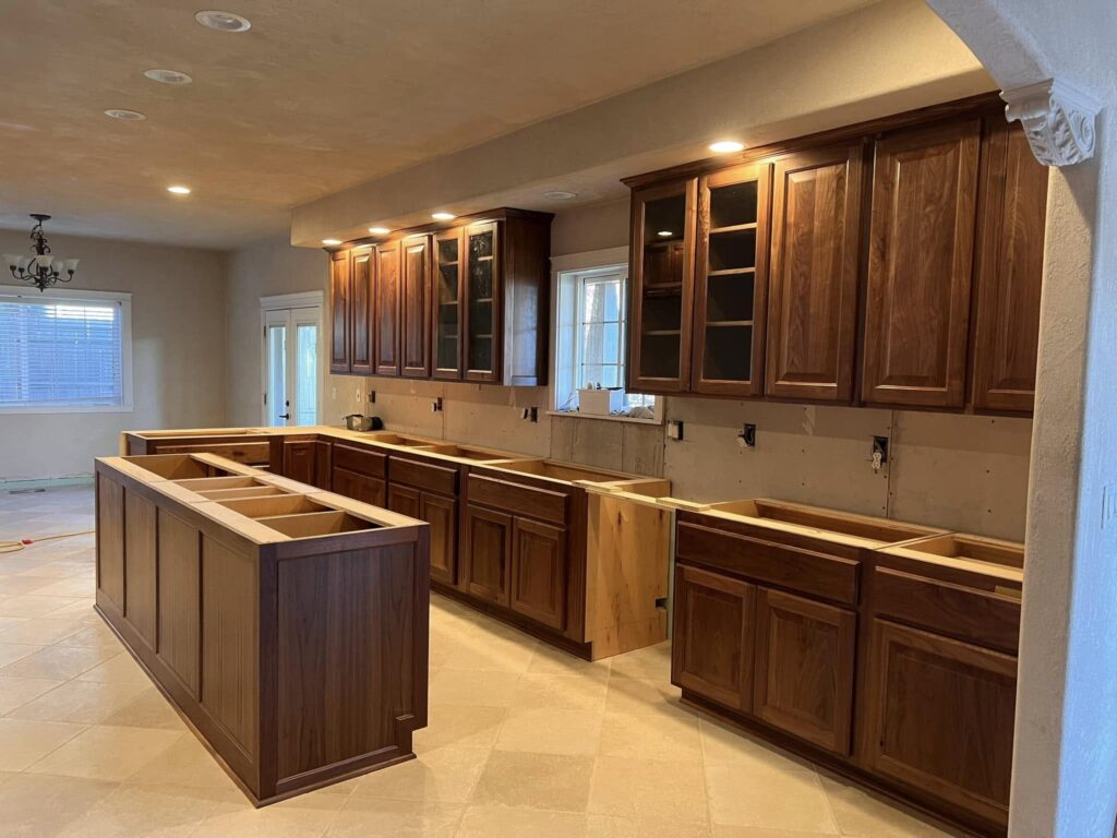 Full view of walnut kitchen cabinetry before countertops